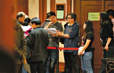 12日,北京丽都饭店,马航工作人员叫乘客家属进屋领取慰问金。目前,马航两次向乘客家属发放慰问金,但未启动赔偿。新京报记者