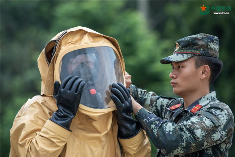 武警官兵相互协同穿戴防护服.