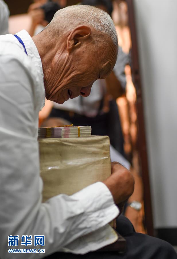 蔡公雨老人抱着哥哥蔡元海的骨灰盒