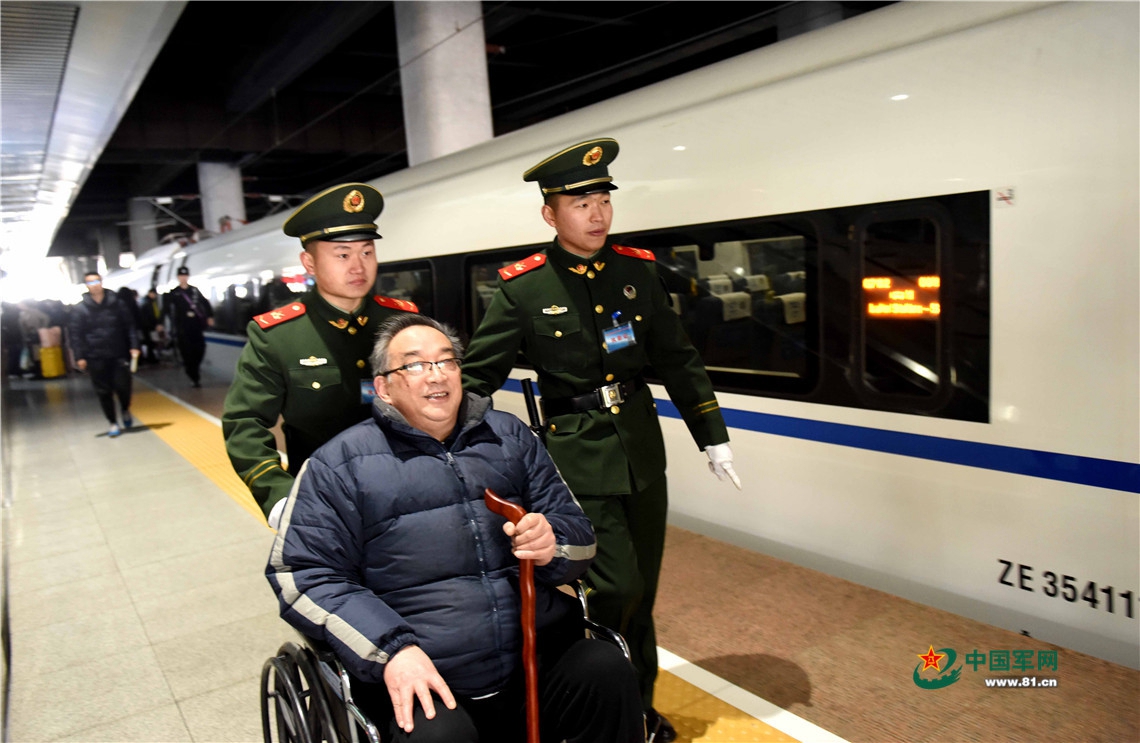 2月12日,在安徽合肥高铁南站,武警执勤战士护送需要帮助的旅客上车.